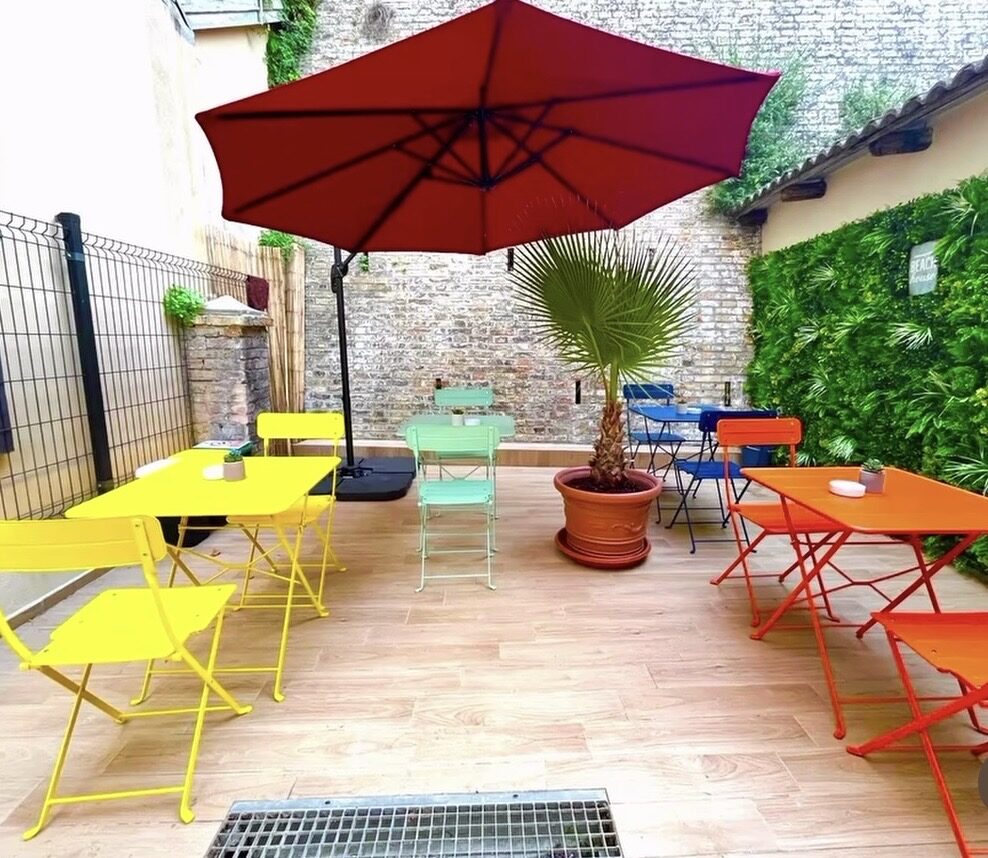 Cortile di Aloha con palma, ombrellone rosso e tavolini colorati